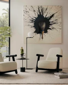 A minimalist living room featuring two white leather armchairs on a beige rug, a black side table with a white globe lamp and