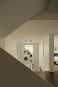 Modern minimalist residential interior with white space, glass accents, and a window view.