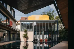 A modernist living space extension featuring glass walls and a pool.