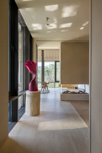 A modern residential interior with concrete flooring, large windows, and a fireplace.