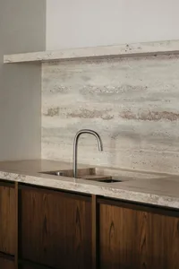Concrete kitchen counter with minimalist faucet and wooden cabinets.