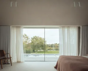 寧靜簡約臥室，配有玻璃簾與地板，可眺望寧靜自然景觀。