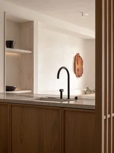 Modern kitchen featuring minimalist design, stone countertops, and wooden cabinetry.