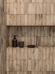 Modern bathroom featuring marble tiles with integrated storage shelves and small black items.