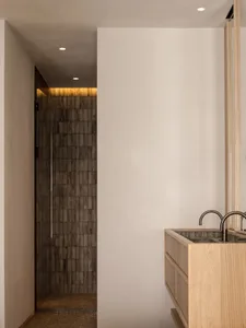 Minimalist bathroom with wood vanity and stone walls.