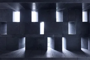A modern interior space with concrete walls and light shining through windows.