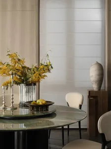 Modern dining room with marble table and chairs, featuring a vase and floral arrangement.
