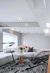 Modern living room with a neutral color palette featuring black and white patterned textiles and minimalist design.