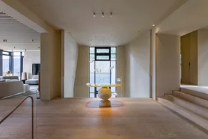 A modern living room with wooden flooring, furniture, and large windows.