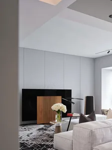 A modern living room featuring minimalist furniture, a wooden cabinet, and a gray sofa.
