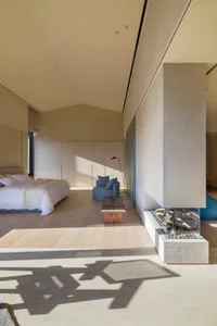 Modern minimalist bedroom with concrete surfaces and a minimalist chair.