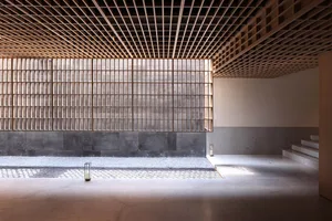 A minimalist interior design featuring wooden ceiling beams and concrete walls.
