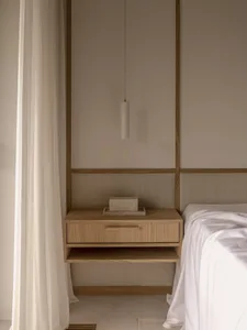 Minimalist bedroom with a floating nightstand, wooden elements, and a sleek pendant lamp.