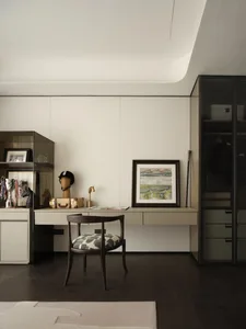 A minimalist home office space featuring a wooden desk, glass cabinet, and metal chair, with a framed abstract painting and v