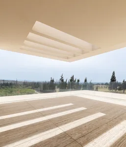 Modern minimalist indoor balcony with concrete floor and clear glass railing overlooking a scenic outdoor landscape.