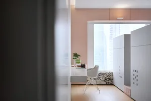 A modern minimalist office space with concrete walls and a sleek white desk and chair.