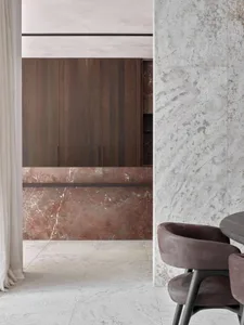 A modern dining room featuring a large marble table and chairs with a minimalist design.