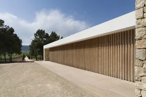 An exterior view of a modern building featuring wood, stone, and concrete materials.