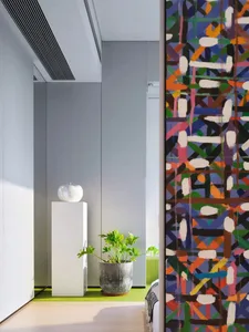 A modern minimalist bedroom with a green potted plant, colorful abstract art, and a white pedestal with an apple decoration.