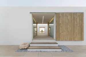 Modern minimalist entryway with concrete walls and wooden upper walls and ceiling, featuring a single light source and a pers