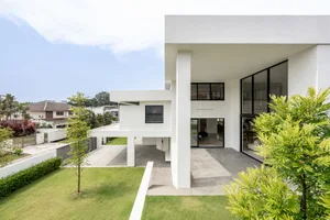 A modern, minimalist house with white walls and large glass windows.