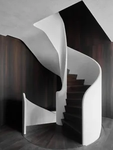 A minimalist staircase with concrete steps, white walls, and dark wooden flooring.