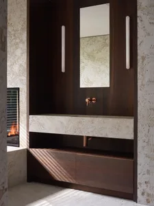 A modern bathroom with a marble sink, wooden vanity, and metal faucet.