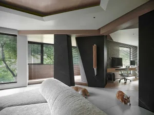 A modern living room featuring minimalist concrete furniture with abstract shapes, large windows with wooden frames, and a sl