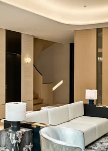 A modern living room with a white sofa, side tables, and wall-mounted lights.