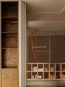 A minimalist living space with wooden shelves filled with books, a metal decorative element, and a concrete floor.
