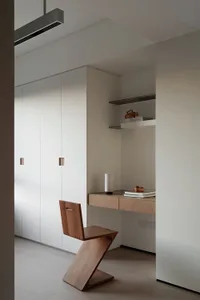 A sleek, minimalist wooden chair with a unique zigzag design, placed in a modern home office setting.