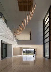 A luxurious modern residential interior featuring polished marble flooring, large glass windows, concrete walls, and contempo