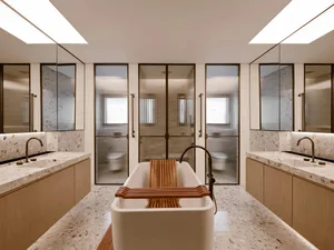 A minimalist bathroom featuring a freestanding tub, terrazzo flooring, and sleek white cabinetry.