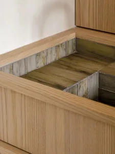 Close-up of a minimalist bathroom featuring wood panels, glass tiles, and metal accents.