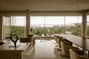Modern commercial space featuring glass and concrete materials, with a cityscape view from the large windows.