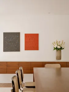 A modern interior design featuring wooden furniture and white walls with art hanging on the wall.