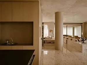A modern living room with concrete walls, marble accents, and minimalist design.