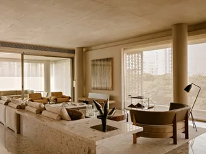 A modern living room featuring a terrazzo floor, minimalist furniture, and large windows with a view of trees.
