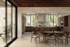 Modern residential kitchen with stone cabinets and wooden furniture.