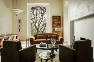 A modern living room with a velvet sofa and wooden cabinet against a wall with a large window.