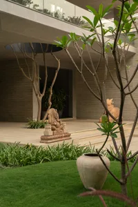 A serene garden landscape featuring a concrete patio, stone sculptures, and lush greenery.