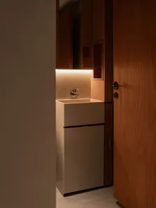 Modern minimalist bathroom with a white ceramic sink and warm lighting.