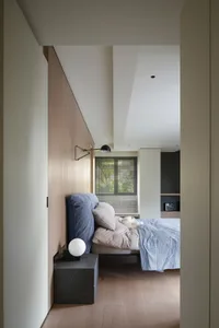A minimalist bedroom with a bed, pillows, and a window with blinds.