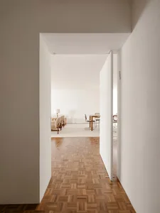 A minimalist living room with wooden flooring and modern furniture.