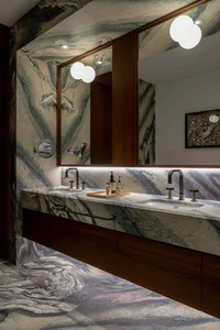 Modern residential bathroom with marble walls, floor, and countertop featuring a floating vanity with a double sink, wood cab