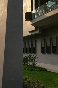 Modern, sleek, concrete building exterior with large glass window panels and green plants in foreground.