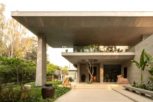 A modern residential entry featuring a concrete structure and lush greenery.