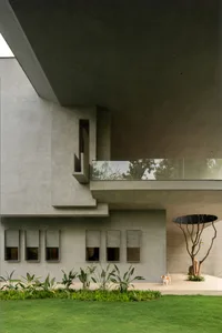 A modern building with a concrete exterior and glass windows, featuring a garden and a dog.