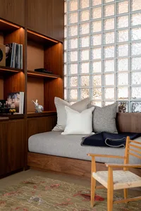 A modern home office featuring a wooden desk, glass block wall, and brick accents