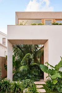 A modern house with a concrete facade and lush greenery in the garden.